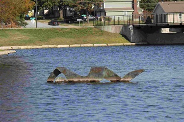 Sculpture of a person swimming in a pond. Swimmer: Sculptor David Hickman's abstract female form “swims” in the pond at Sar-Ko-Par Trails Park every summer, but is stored for safety during the cold seasons.