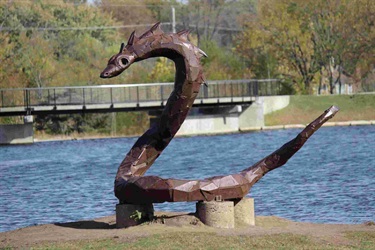 Welded steel and wood snake. The Serpent: Area kids delight in climbing on J. Derek Arnold's “The Serpent,” a welded-steel and wood creation that guards Snake Island in the pond at Sar-Ko-Par Trails Park.