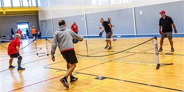 Group of men playing pickleball in gym
