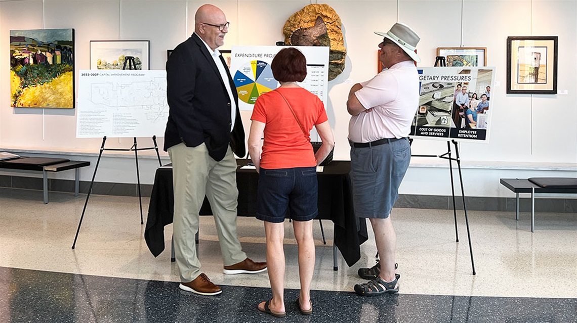 City staff member talking with woman and man in front of budget display boards
