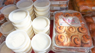 Bird's-eye view of trays of cinnamon rolls and containers of frosting