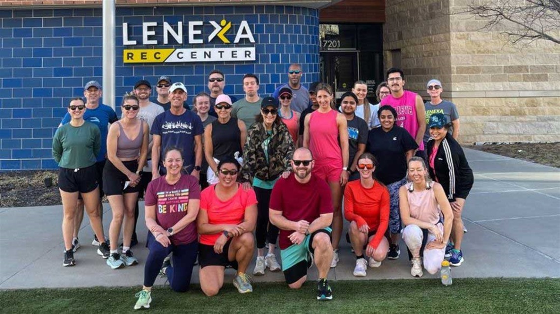 Group of people in running clothes pose outside Lenexa Rec Center
