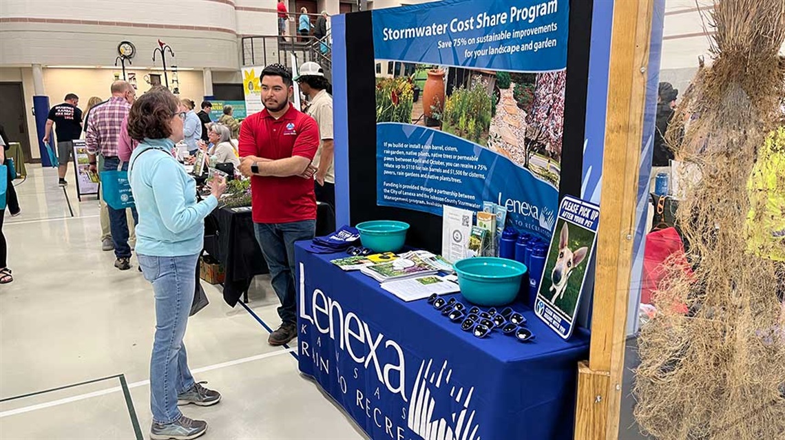 Woman and man speak next to Lenexa Rain to Recreation booth about Stormwater Cost Share Program