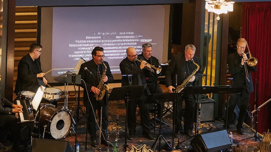 Seven people from the Kansas City Jazz Orchestra playing instruments on a stage