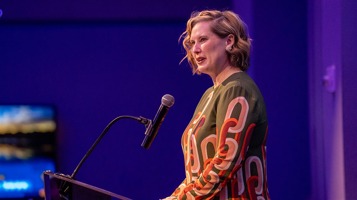 Woman speaks at a podium in a ballroom