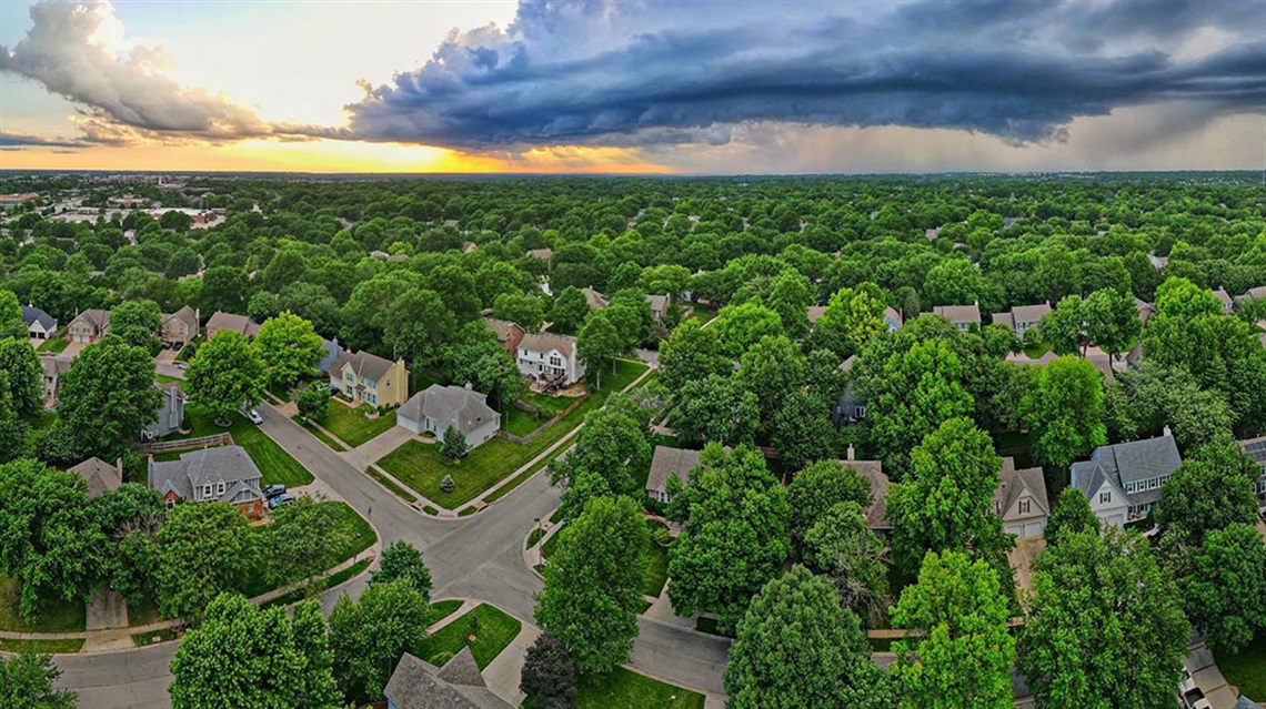 bird's eye view of houses and trees with heavy clouds above