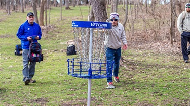 Man doing short throw to disc golf basket