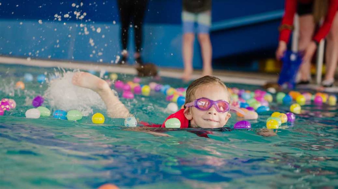 Girl in pool with plastic eggs surrounding her