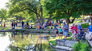 Adults helping kids fish at Rose's Pond at Sar-Ko-Par Trails Park.