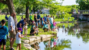 People standing or sitting while fishing at the edge of Rose's Pond at Sar-Ko-Par Trails Park.