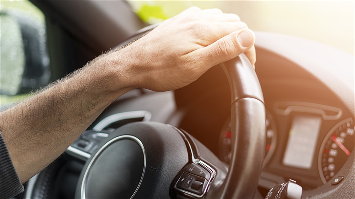 Hand on steering wheel in car