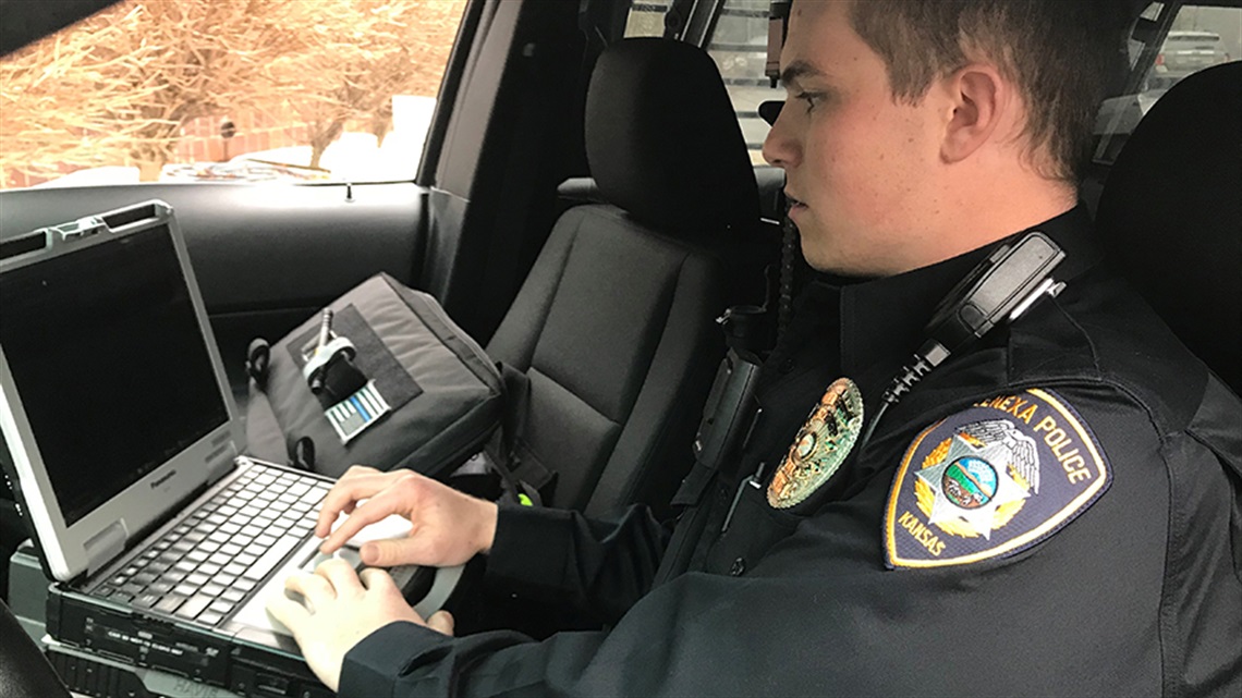 Officer in car on laptop