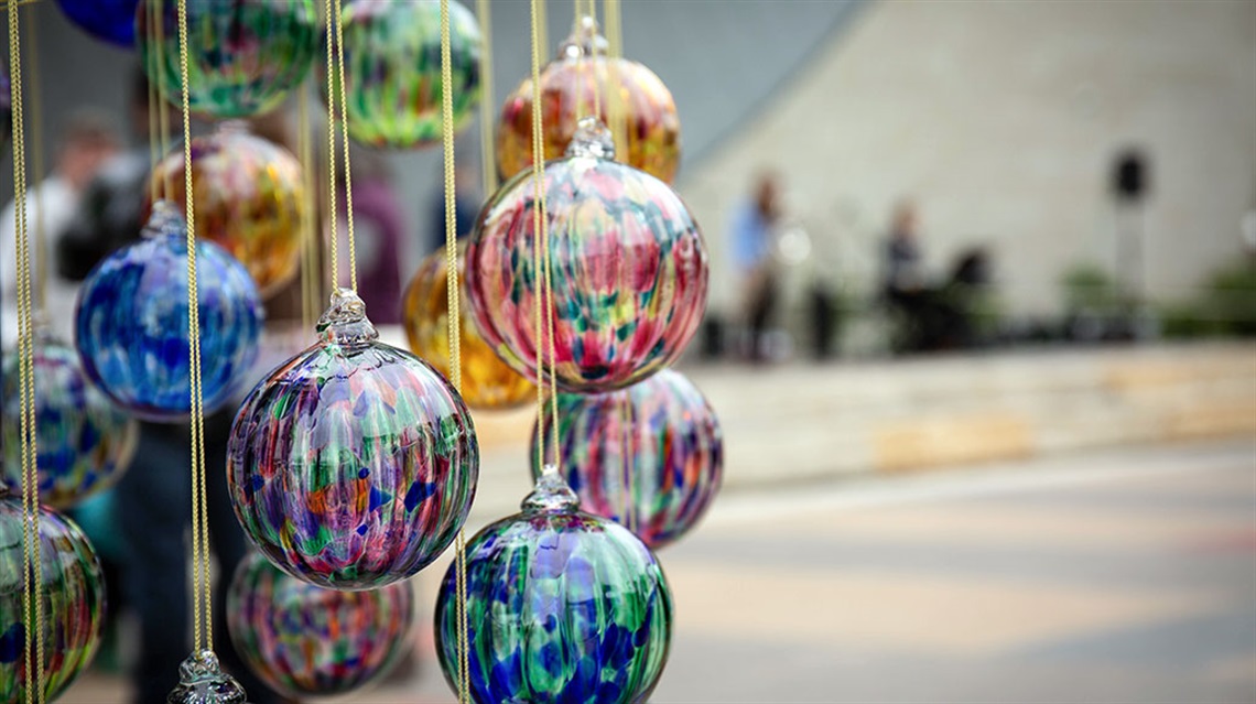 colorful glass globes art hanging in foreground with musicians playing on stage in background