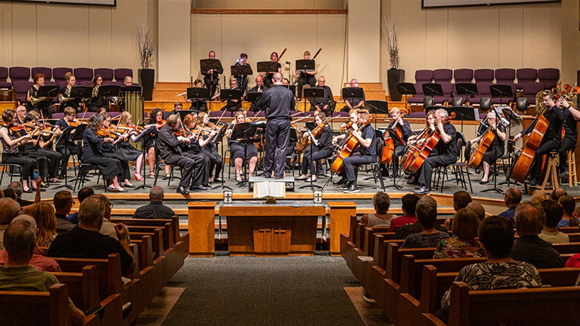 Orchestra performing a concert for an audience inside a church