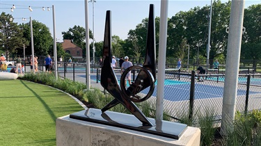 Sculpture representing jogger on concrete pedestal with pickleball courts in background