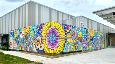 Colorful mural on two sides of building exterior depicting Lenexa history