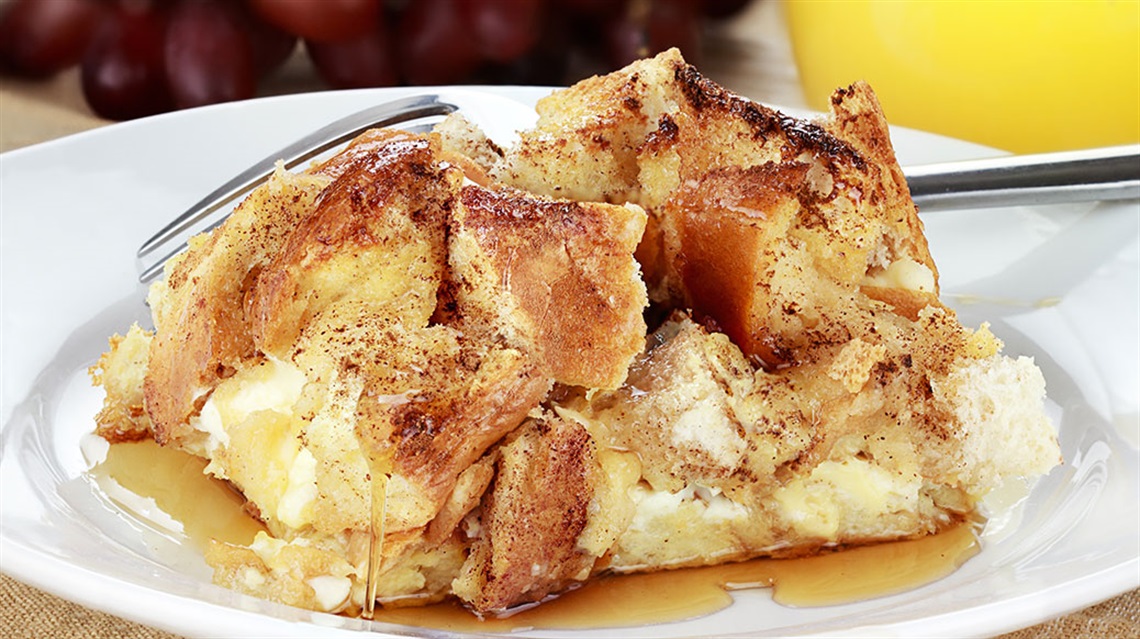 Slice of brioche French toast casserole on white plate with a fork