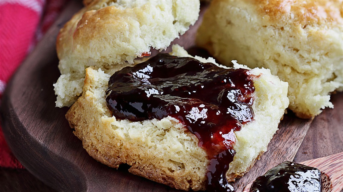 Closeup of biscuits split open and spread with jam