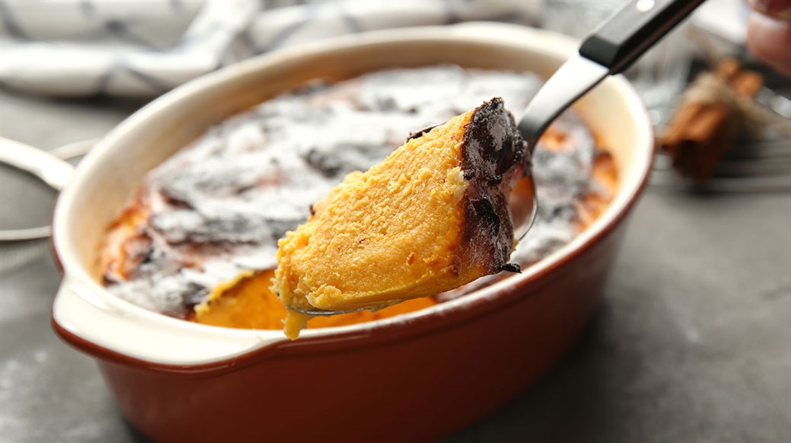 Spoon scooping carrot souffle out of baking dish