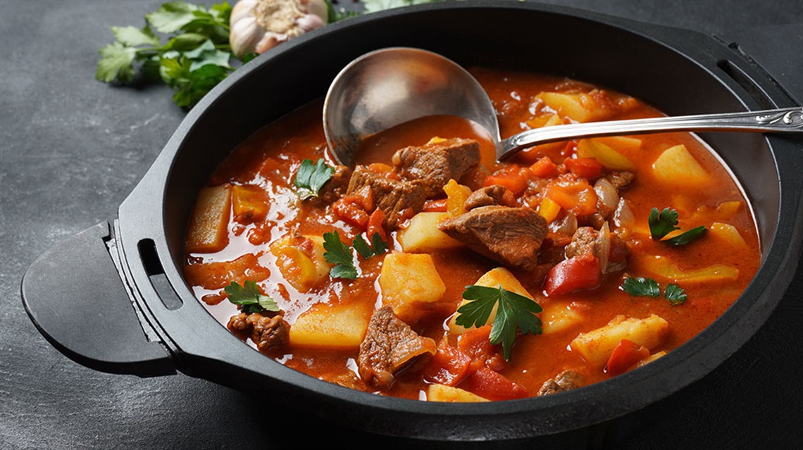 Pot of beef and vegetable stew with a ladle
