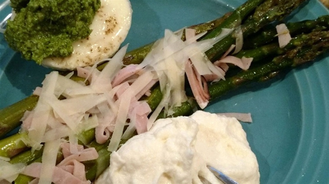Closeup of grilled asparagus with whipped ricotta and poached egg on plate