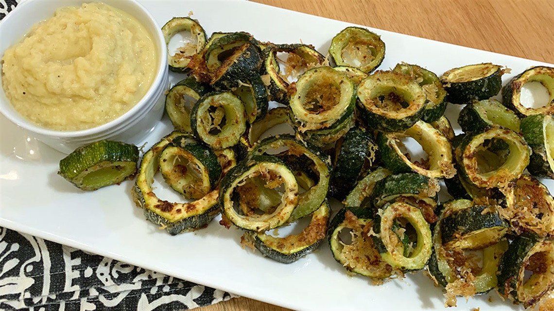 Platter of parmesan zucchini rings with a bowl of dipping sauce