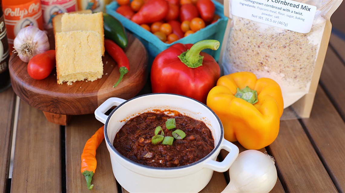 bowl of chili surrounded by cornbread, cornbread mix and vegetables