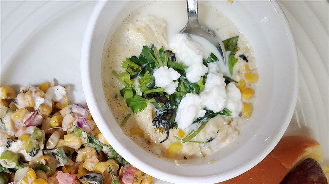 bowl of roasted corn and poblano soup topped with cilantro and Cotija cheese