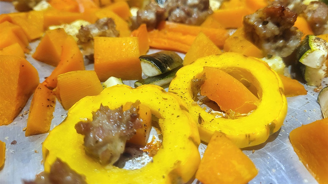 sliced and chopped squashes, carrots and sausage on a sheet pan