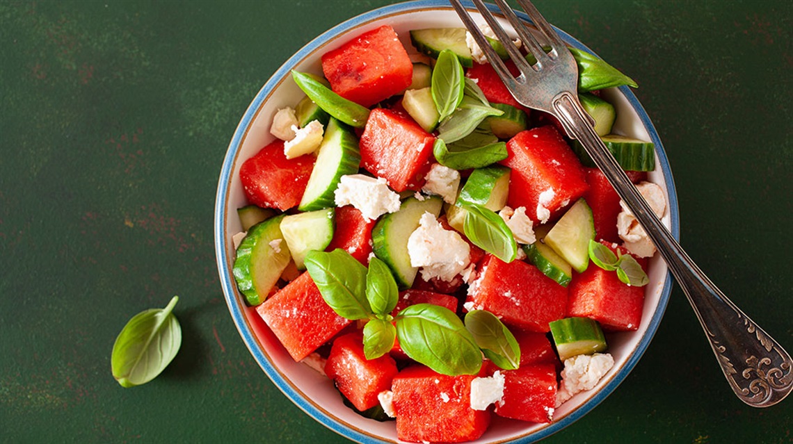 fork sitting atop bowl of watermelon cucumber salad with feta