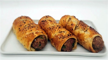 Three sausage rolls arranged diagonally on white plate