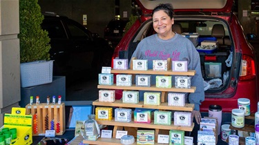 Woman stands behind table display of bar soaps and other products