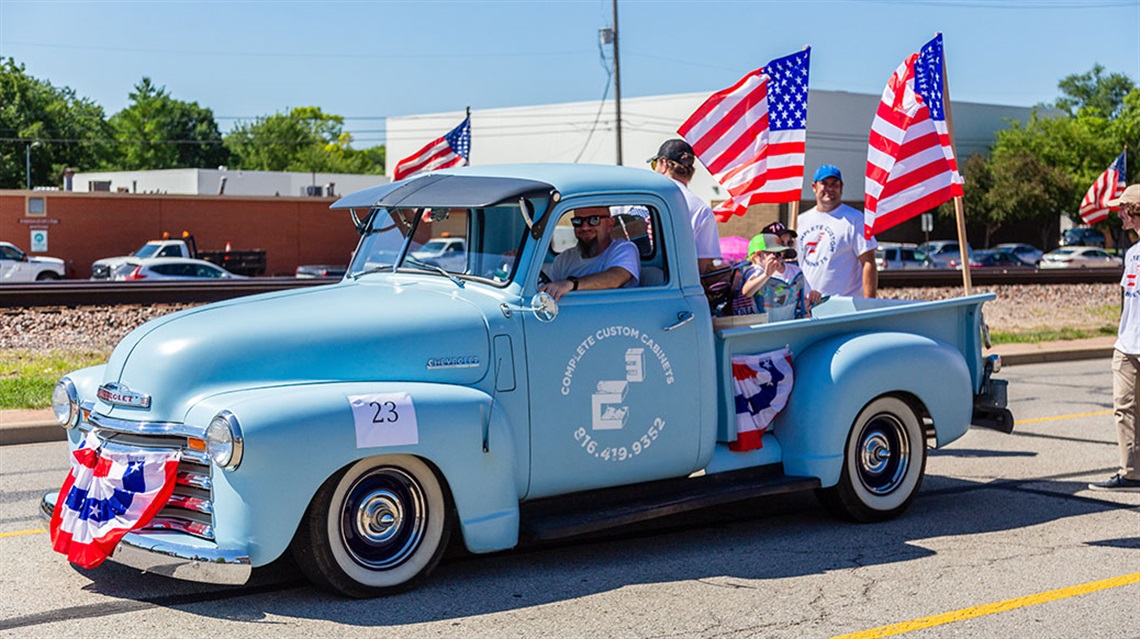 vintage blue truck with patriotic decorations in parade