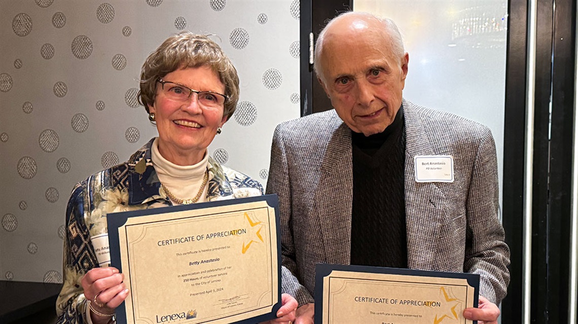 senior woman and man holding certificates of appreciation