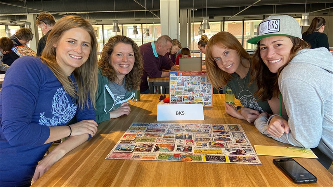 four women posing with completed jigsaw puzzle