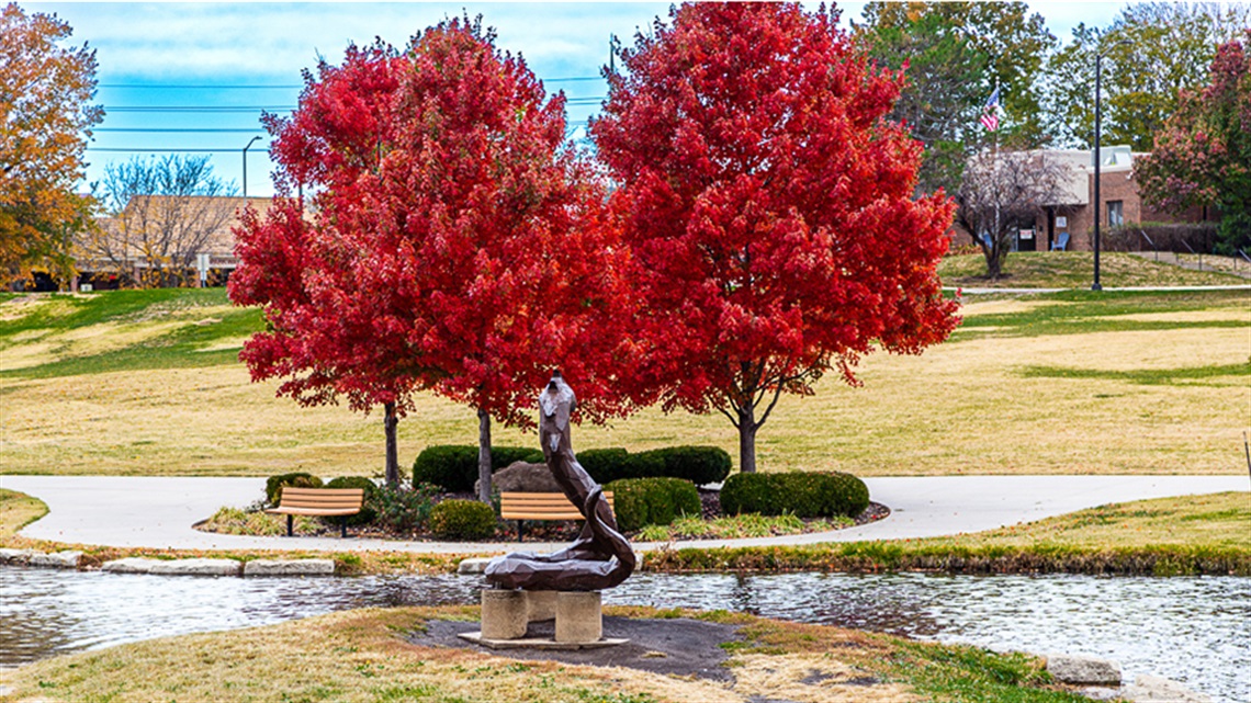Colorful fall trees in park with statue of serpent