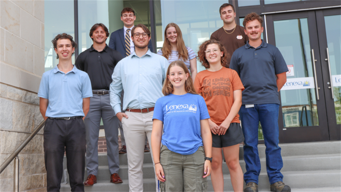 Group of nine interns smiling and standing on stairs outside of Lenexa City Hall.