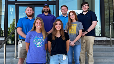 Group of seven interns smiling and standing on stairs outside of Lenexa City Hall
