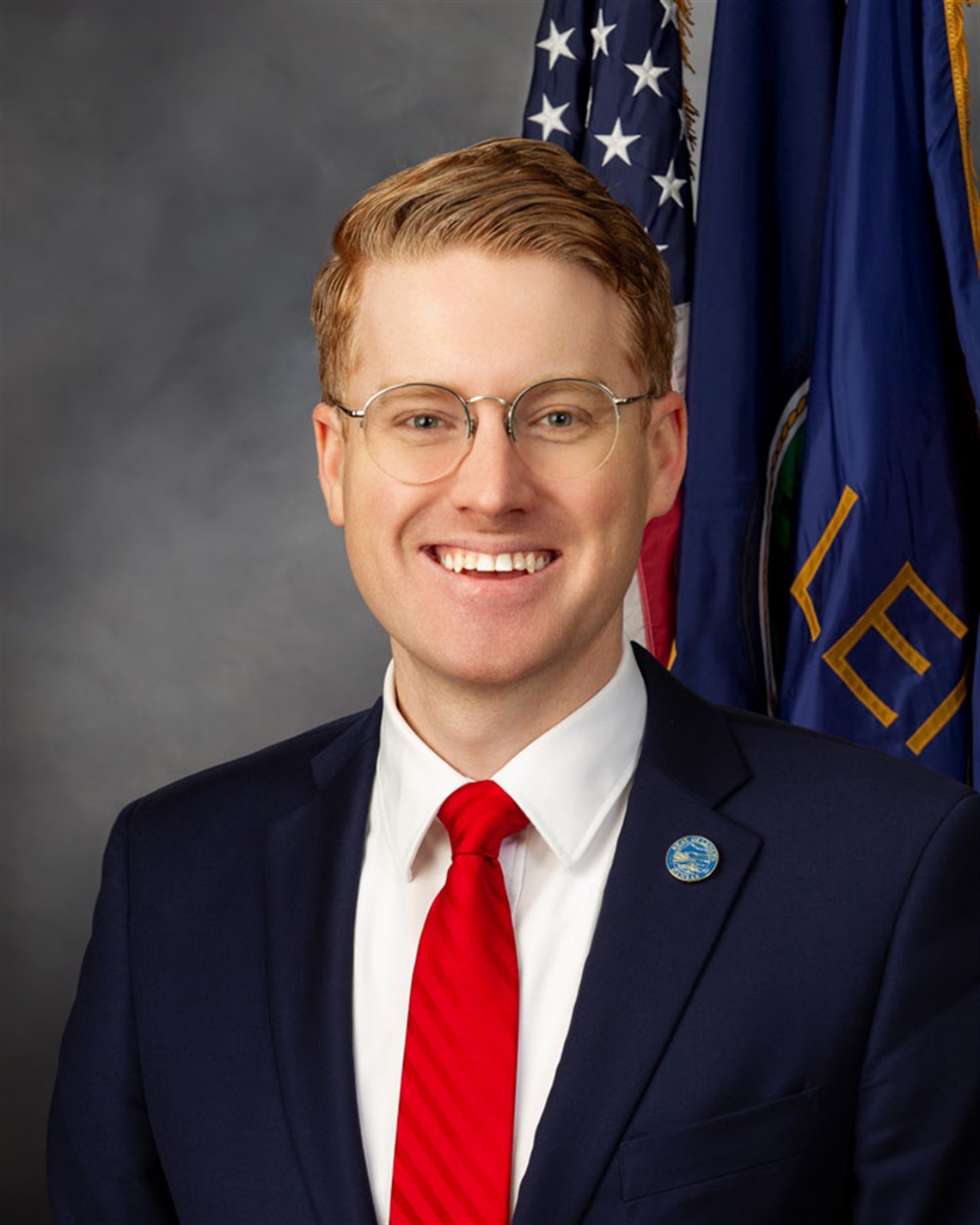 Head shot of smiling man in suit with U.S. and City of Lenexa flags in background