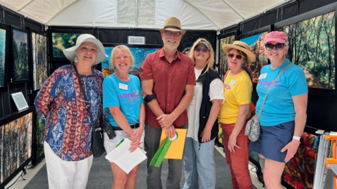 Several Lenexa Arts Council members pose with staff and artist at Lenexa Art Fair.