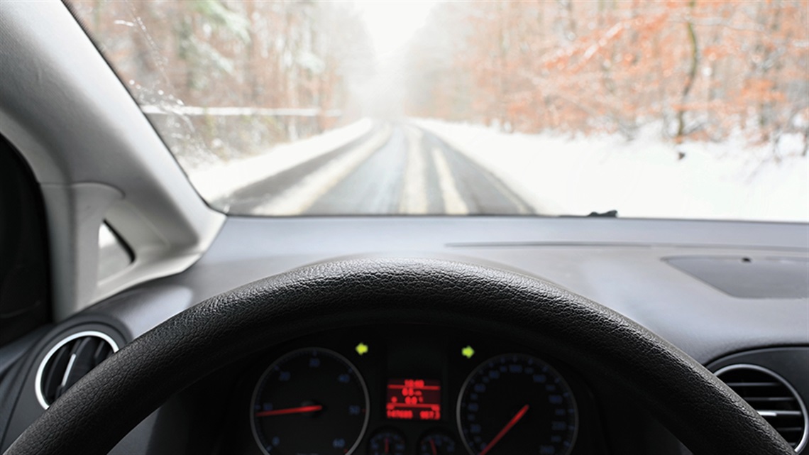 View from driver's seat of car looking over steering wheel onto snowy road