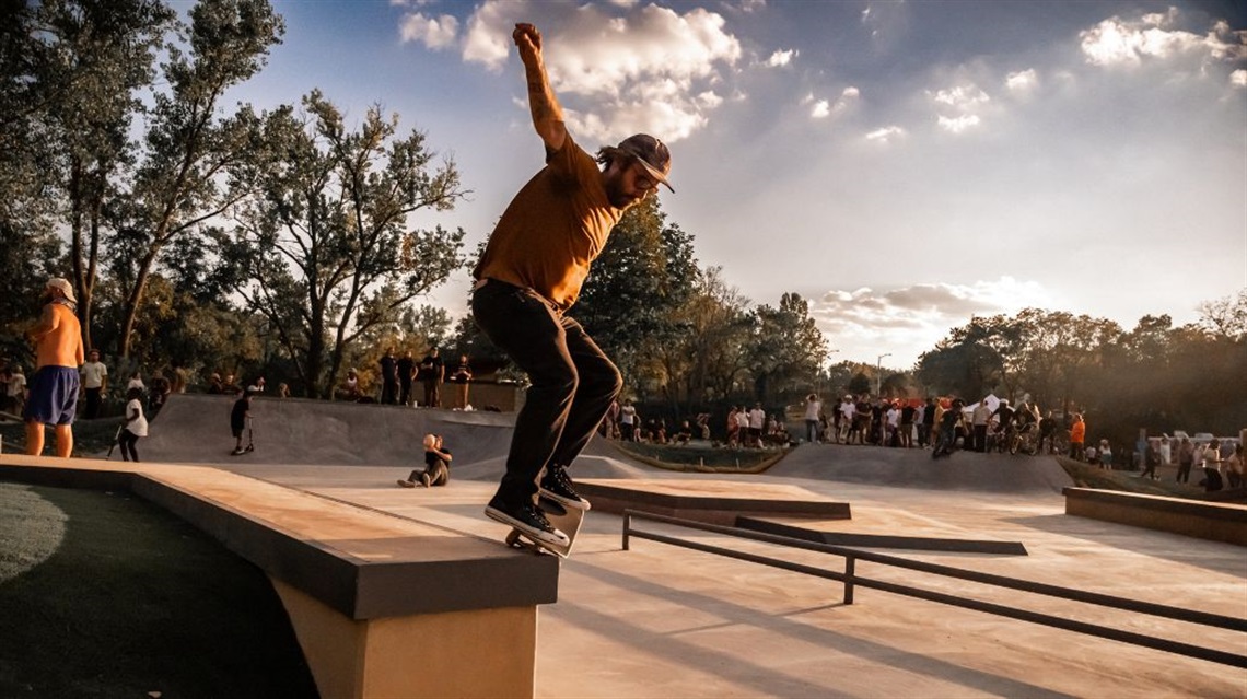 Man on skateboard riding on edge of stone wall at a skate park