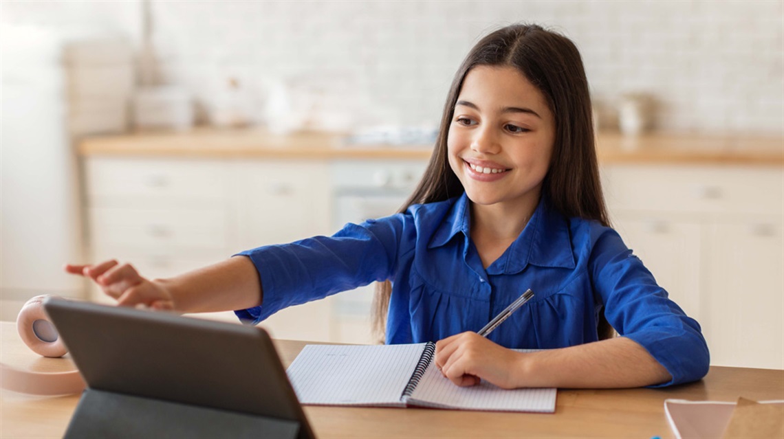 Smiling young girl with notepad using tablet