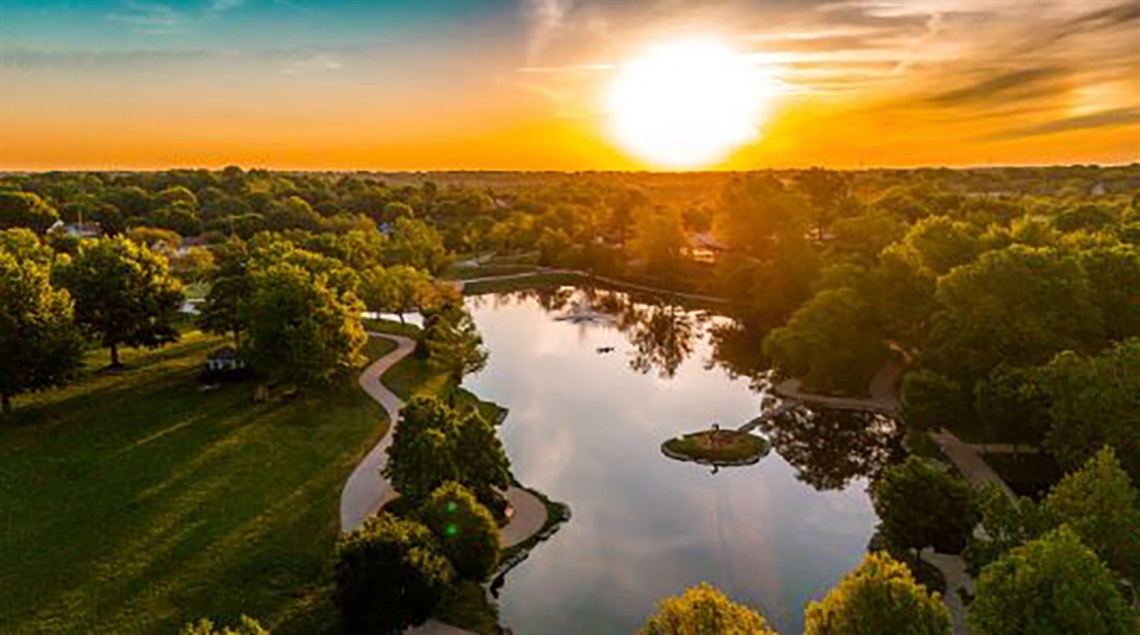 Bird's-eye view of sunrise over park with pond