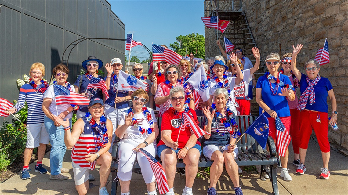 Large group of people dressed in red, white and blue and holding American flags