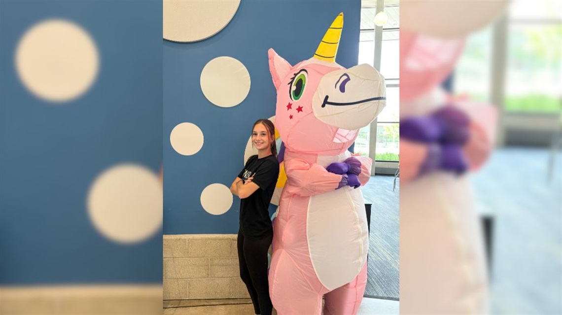 Adelyn posing with a giant inflatable unicorn mascot