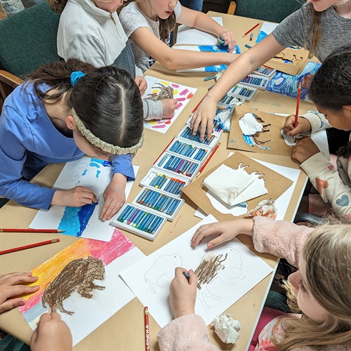 Kids coloring bison on paper at a table