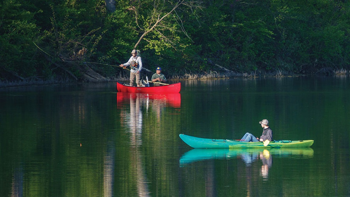 Men fishing in canoe and man floating in kayak