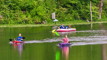 People kayaking and riding in other boat