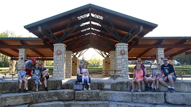 Families sitting on rocks in front of Oak Shelter